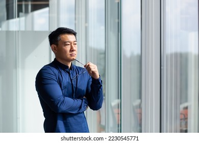 Successful Asian businessman thinking by the window, man in shirt and glasses investor thinking about future plans. - Powered by Shutterstock