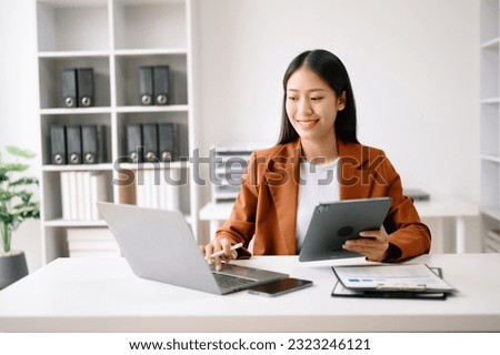 Successful Asian Businesswoman Analyzing Finance on Tablet and Laptop at modern Office Desk tax, report, accounting, statistics, and analytical research concept
