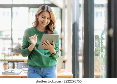 Successful Asian businesswoman working at home using a tablet. surf the internet play social media creative planning work - Powered by Shutterstock