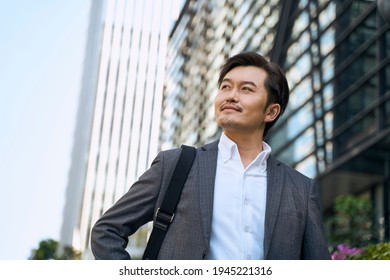 successful asian corporate executive walking in central business district of modern city