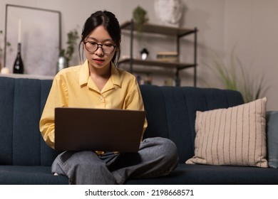 Successful Asian Female Freelancer Using Laptop Computer Working Online Sitting At Home, Wearing Eyeglasses. Distance Job, Freelance Career And Business Concept