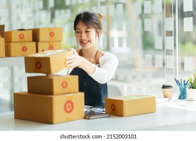Successful Asian women entrepreneur with parcel boxes in her own job shopping online business at home office. start up small business, sme concept.