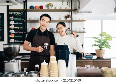 Successful Asian Young Male And Female Barista Cafe Entrepreneur Holding Coffee Filter And Standing Inside The Coffee Counter Bar. Small Business Coffee Shop Owner.