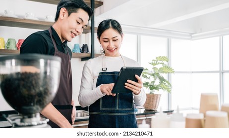 Successful Asian Young Male And Female Barista Cafe Entrepreneur Check Coffee Buy Order From A Digital Tablet. Small Business Coffee Shop Owner. Image With Copy Space.