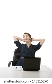 Successful attractive young businesswoman relaxing at her desk sitting back comfortably in her chair with her hands clasped behind her head and a delightful smile