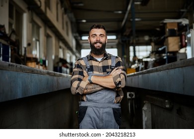 A successful auto-mechanic standing with arms crossed in car mechanic's pit with arms crossed and looking at camera. Auto-mechanic in his workshop - Powered by Shutterstock