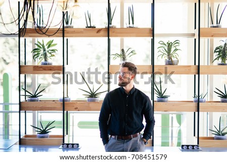 Successful bearded businessman standing in his office