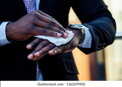 Successful And Beautiful American Afro Man In A Dark Business Suit In A White Shirt Using Wet Wipes