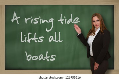 Successful, Beautiful And Confident Woman Showing A Rising Tide Lifts All Boats On Blackboard