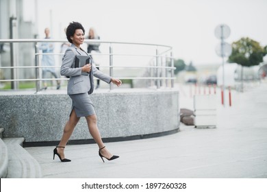 A Successful Black Business Woman While Walking Down A Stairs In Front A Corporate Building.