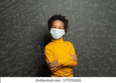 Successful black child boy student in protective face mask on black chalkboard background