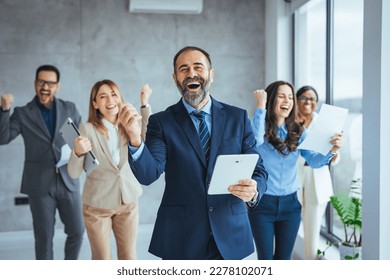 Successful business group celebrating an achievement at the office with arms up and looking at the camera smiling. Shot of a group of young businesspeople huddled together in solidarity in a office - Shutterstock ID 2278102071