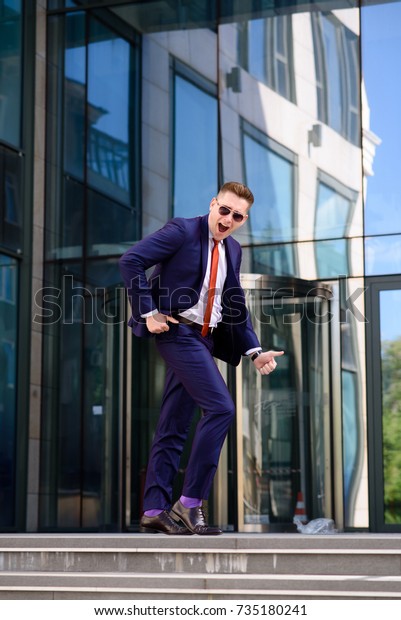 A\
successful business man dances on the\
street.