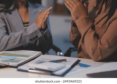 A successful business meeting with teamwork and collaboration, featuring a diverse group of professionals, including a young Asian businesswoman, in a modern office setting. - Powered by Shutterstock