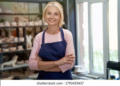 Successful business owner. Portrait of beautiful happy craft woman wearing apron looking at camera and smiling while standing in her art studio or craft pottery shop - Shutterstock ID 1792433437