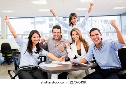 Successful business team with arms up at the office - Shutterstock ID 127070438