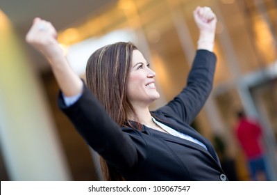 Successful business woman with arms up celebrating