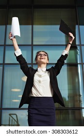 Successful business woman with arms up and documents. Happy young business woman made a deal. Business peolple concept