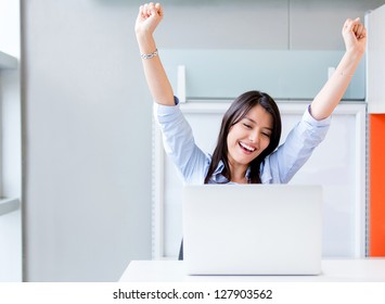 Successful business woman with arms up at the office