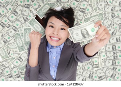 successful business woman hold fist with money and lying on money bed, asian beauty model