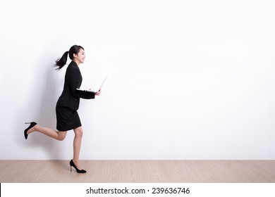 Successful Business Woman Running And Hold Laptop Computer With White Wall Background, Great For Your Design Or Text, Asian