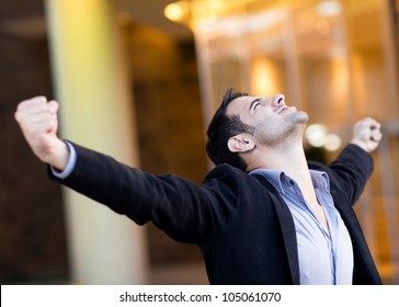 Successful businessman with arms up celebrating his victory