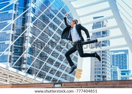 Successful businessman celebrating his victory with jump up in feeling happy on cityscape background.