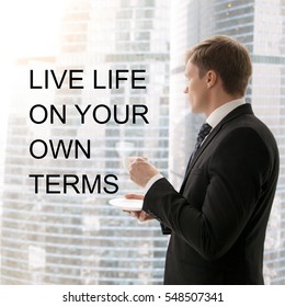 Successful businessman in classical formal suit standing in office, looking through window at big city skyscrapers, drinking coffee. Photo with motivational text "Live life on your own terms"