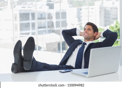 Successful businessman in his office relaxing with his feet on his desk