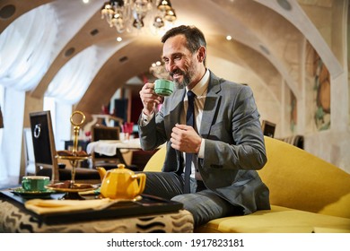 Successful Businessman Looking Inspired While Having His Cup Of Tea And Sitting In Hotel Lounge