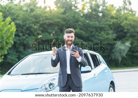 Successful businessman man rejoices in victory, man wins car in phone app, looks at phone and shouts of joy and euphoria of happiness