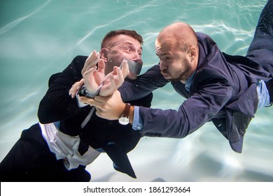 Successful Businessman Rescues Young Business Start-up With His Mouth Taped Shut And His Hands Tied Underwater. Saving Competitors. Concept Of Helping, Partnership, And Goal Achievement. Copy Space