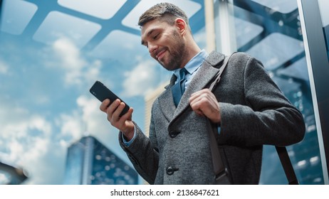 Successful Businessman Riding Glass Elevator to Office in Modern Business Center. Handsome Happy Man Smile while Using Smartphone, Write Text Message, Check Social Media and Work Emails in a Lift. - Powered by Shutterstock