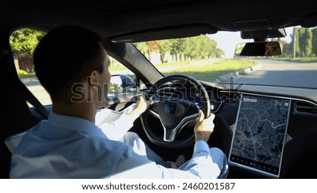 Successful businessman riding on electrical vehicle at city. Male entrepreneur driving a modern electric car at urban road. Businessperson operating auto at sunny day. Young man commuting to work