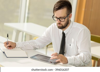 Successful businessman sitting in an office and writing some notes in his planner - Shutterstock ID 396016207