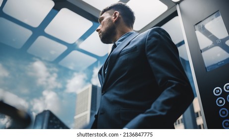 Successful Businessman in a Suit, Looking out of the Window, While Riding Glass Elevator to Office in Modern Business Center. Handsome Top Manager Ready for Important Meeting. - Powered by Shutterstock