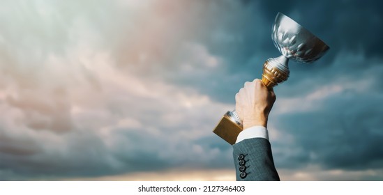 successful businessman with trophy in hand on sky background. business success and achievement concept. copy space - Powered by Shutterstock