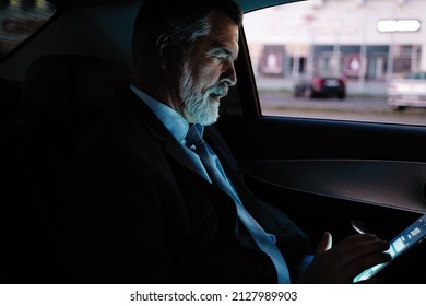 Successful Businessman Working On Phone In Car. Mature Smiling Business Man In Formal Using Smartphone While Sitting On Back Seat Of Business Car. Happy Senior Man Reading Email.