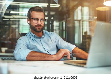 Successful businessman. Young bearded man in eyeglasses and formal wear working with laptop while sitting in the modern office - Shutterstock ID 1481268632