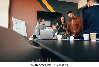 Successful businesspeople discussing some reports in a boardroom. Group of multicultural businesspeople standing around a table in a modern office. Diverse entrepreneurs collaborating on a project. - Powered by Shutterstock