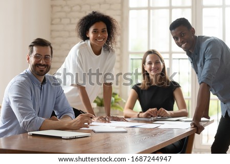 Successful businesspeople portrait, promoted employees, creative department workgroup working on common project concept. Five multi-ethnic business people gather in boardroom smiling posing for camera