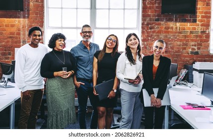 Successful businesspeople smiling cheerfully in an office. Group of happy businesspeople standing together in a creative workplace. Business colleagues enjoying working together. - Shutterstock ID 2062826921