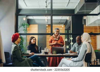 Successful businesspeople smiling happily during a meeting in a creative office. Group of cheerful business professionals working as a team in a multicultural workplace. - Shutterstock ID 2235563205