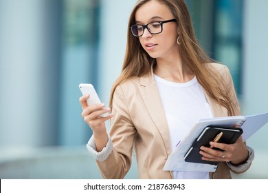 Successful businesswoman with cellphone while walking outdoor. City business woman working.