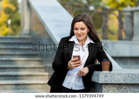 Successful businesswoman with coffee talking on cellphone while walking outdoor. City business woman working.