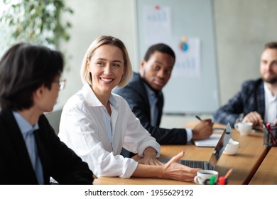 Successful Businesswoman On Corporate Meeting Smiling To Asian Businessman Colleague Discussing Business Project Sitting At Desk In Modern Office. Business Negotiation, Comunication, Networking