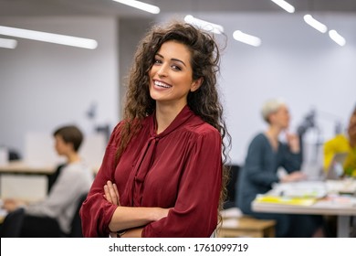 Successful businesswoman standing in creative office and looking at camera while smiling. Portrait of beautiful business woman standing in front of business team at modern agency with copy space. - Shutterstock ID 1761099719