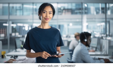 Successful Businesswoman in Stylish Dress Holding Tablet Computer, Standing in Modern Diverse Office Working on Financial, Business and Marketing Projects. Portrait of Beautiful Asian Manager. - Powered by Shutterstock