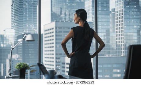 Successful Businesswoman in Stylish Dress Looking out of the Window at Big City in Downtown Area. Confident Female CEO Working on Financial Projects. Manager at Work Planning Marketing Campaign. - Shutterstock ID 2092362223