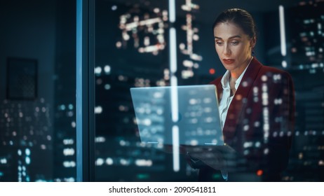 Successful Businesswoman in Stylish Suit Working, on Laptop Looking in Wonder at Night City. Smiling Female CEO Working Late on Computer to Create e-Commerce Online Shopping Product to Customers - Shutterstock ID 2090541811